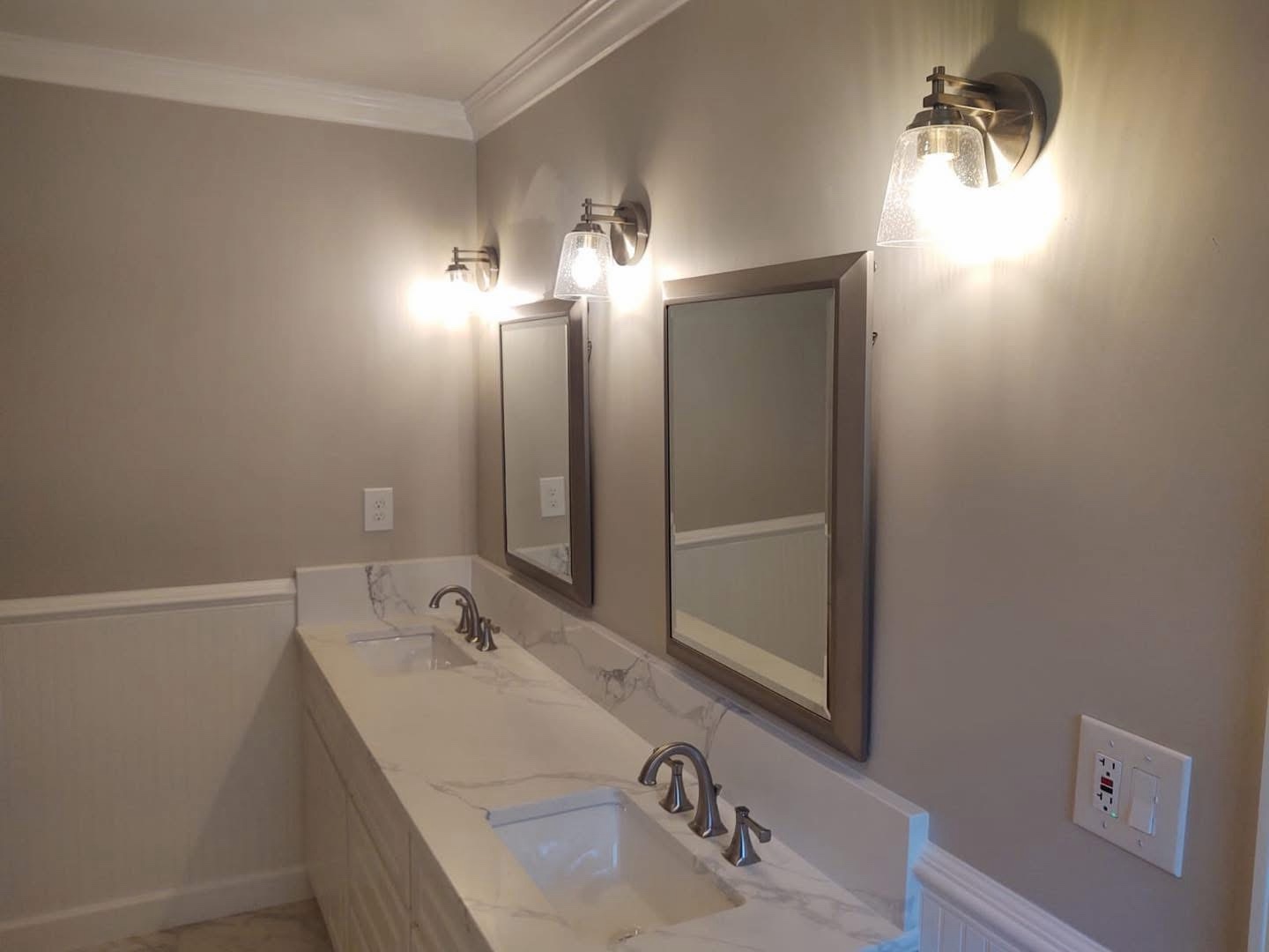 A veined double-sink countertop with brushed-metal fixtures and framed mirrors