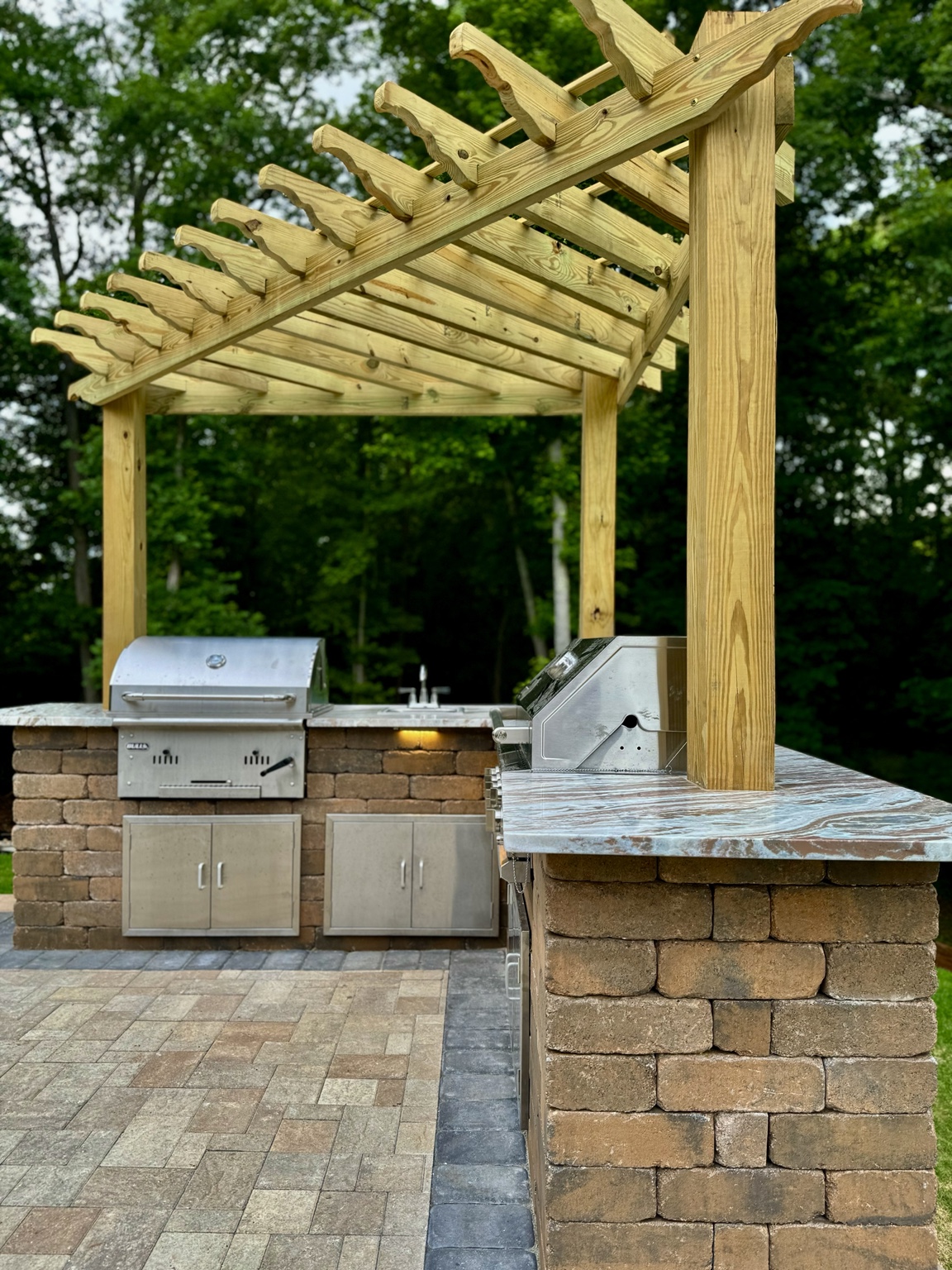 An outdoor kitchen and timber pergola built into a residential landscape
