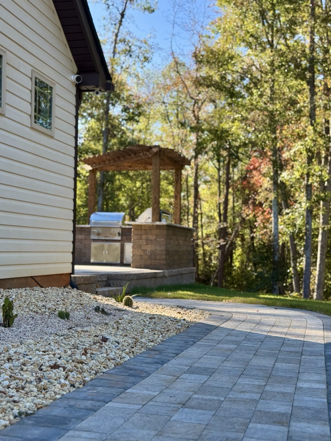 A paver walkway connecting a home to an outdoor kitchen